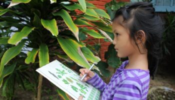 Asian children learning biology plant species outside the classroom.