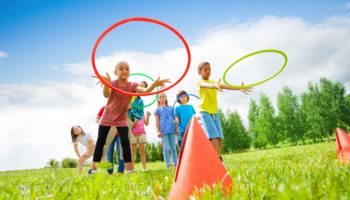 Kids throw colorful hoops on cones while competing